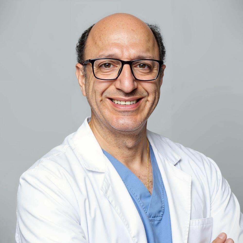 Man wearing a white coat and glasses against a gray background