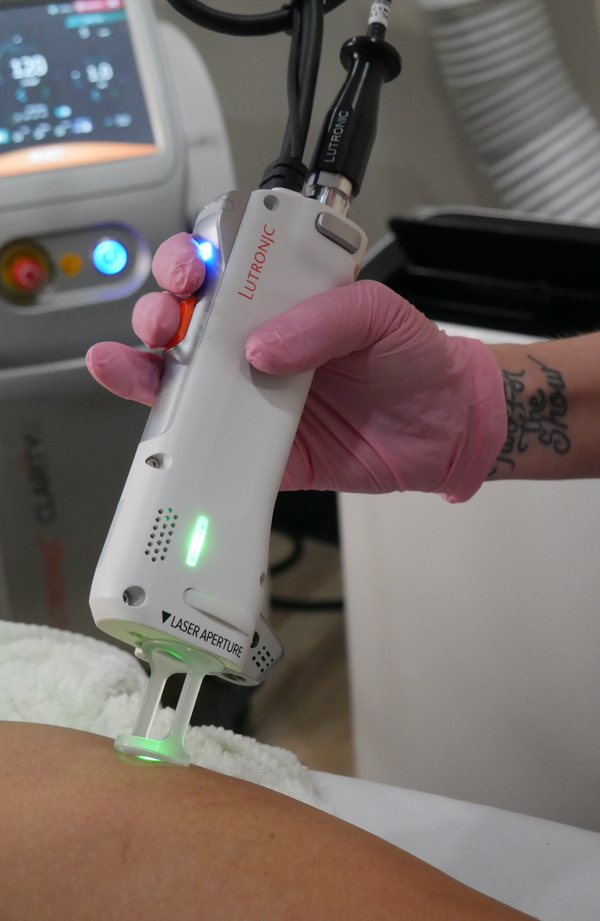 Person wearing gloves holding a laser device on a medical setting