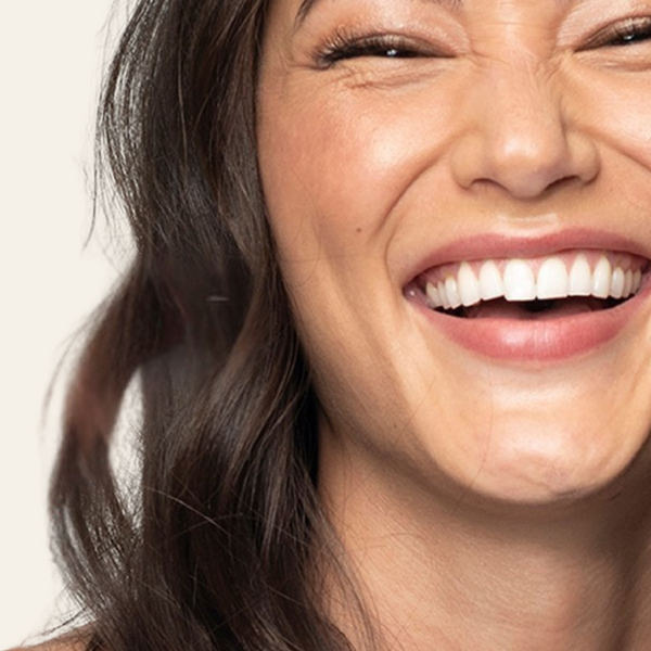Close-up of a woman with a bright smile on a plain background