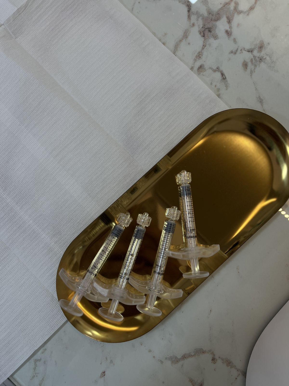 Gold soap dish with multiple bars of soap on a marble surface